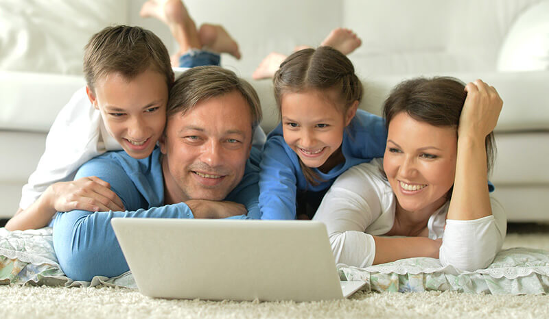 Family with young kids gathered around laptop, tax free savings