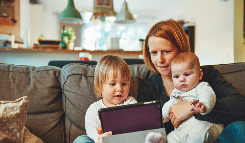 Women with toddler and baby looking at tablet